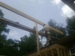 Carpenter setting a ridge beam over a new addition frame — Ice Dam Removal by Roofing Brothers in Snook