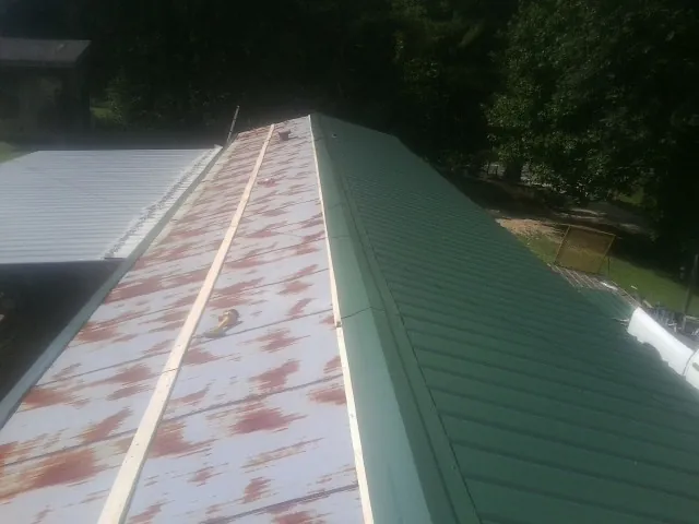 Old rusted panels beside newly installed green metal roofing — Wind Damage Roof Repair by Roofing Brothers in Snook