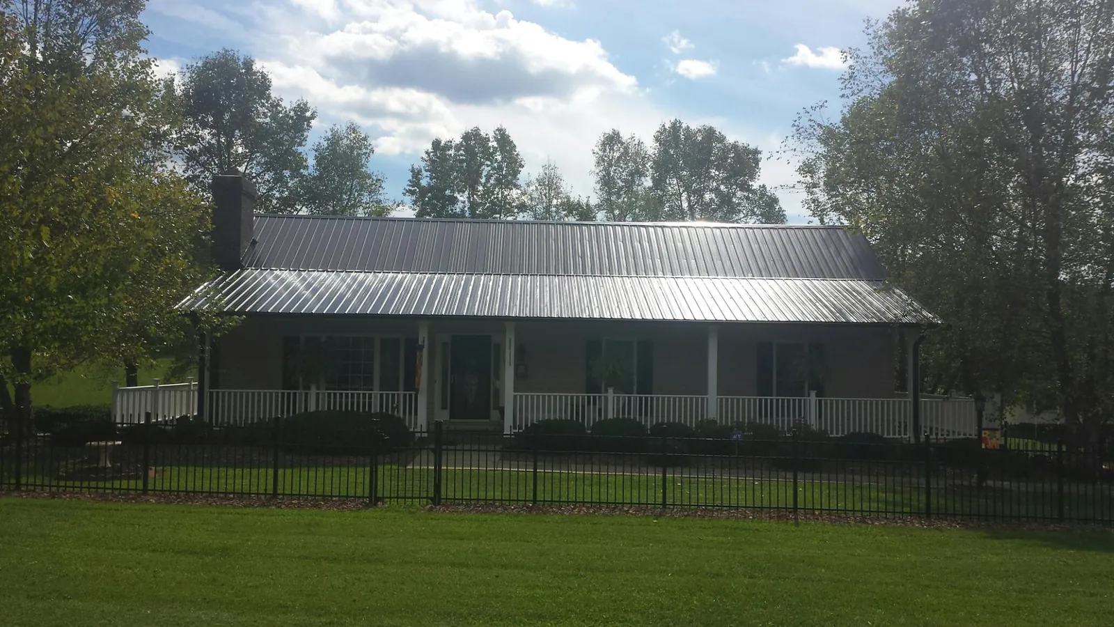Gray metal roof on a brick ranch with a full width front porch — Gutter Guard Installation work by our crew in Snook