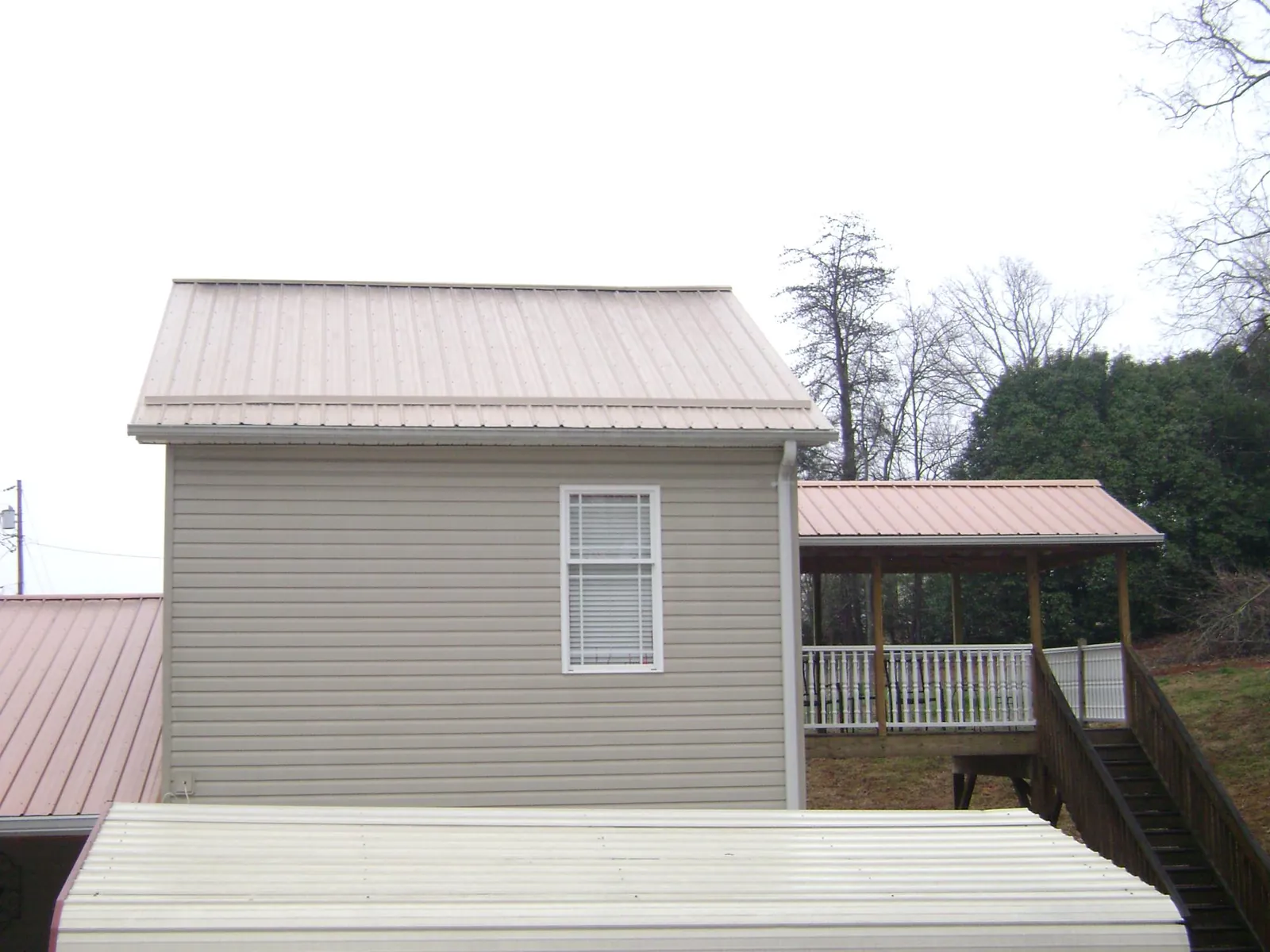Tan metal roofs on a two story addition and attached porch, from a Roof Replacement job in Snook