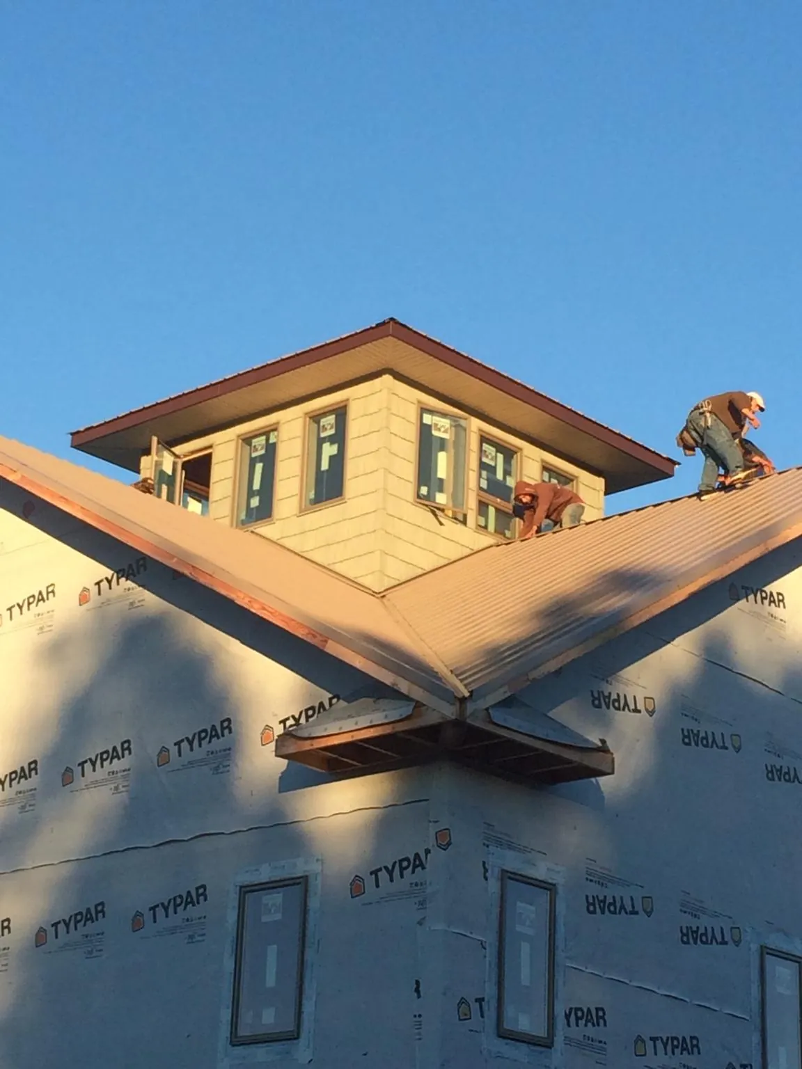 Roofers working around a rooftop cupola on a new metal roof at sunset — Roof Waterproofing in Snook by Roofing Brothers